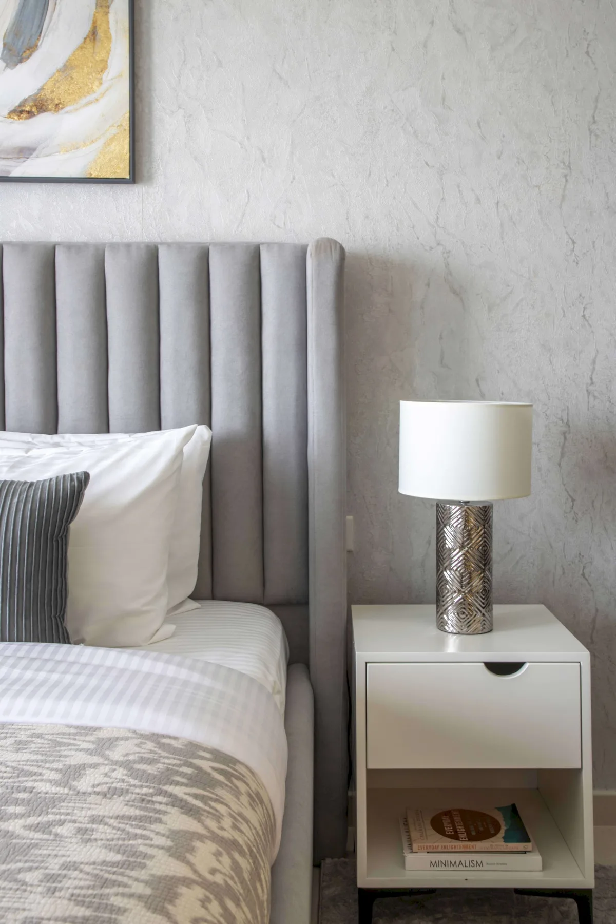 A bedroom with a bed beside a nightstand and table lamp.