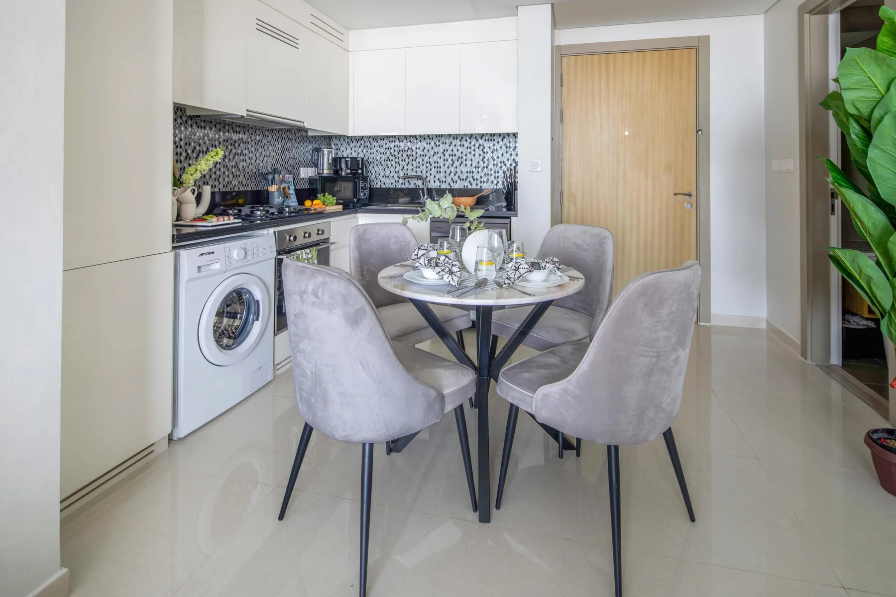 A compact kitchen and dining area with a round table and upholstered seating.