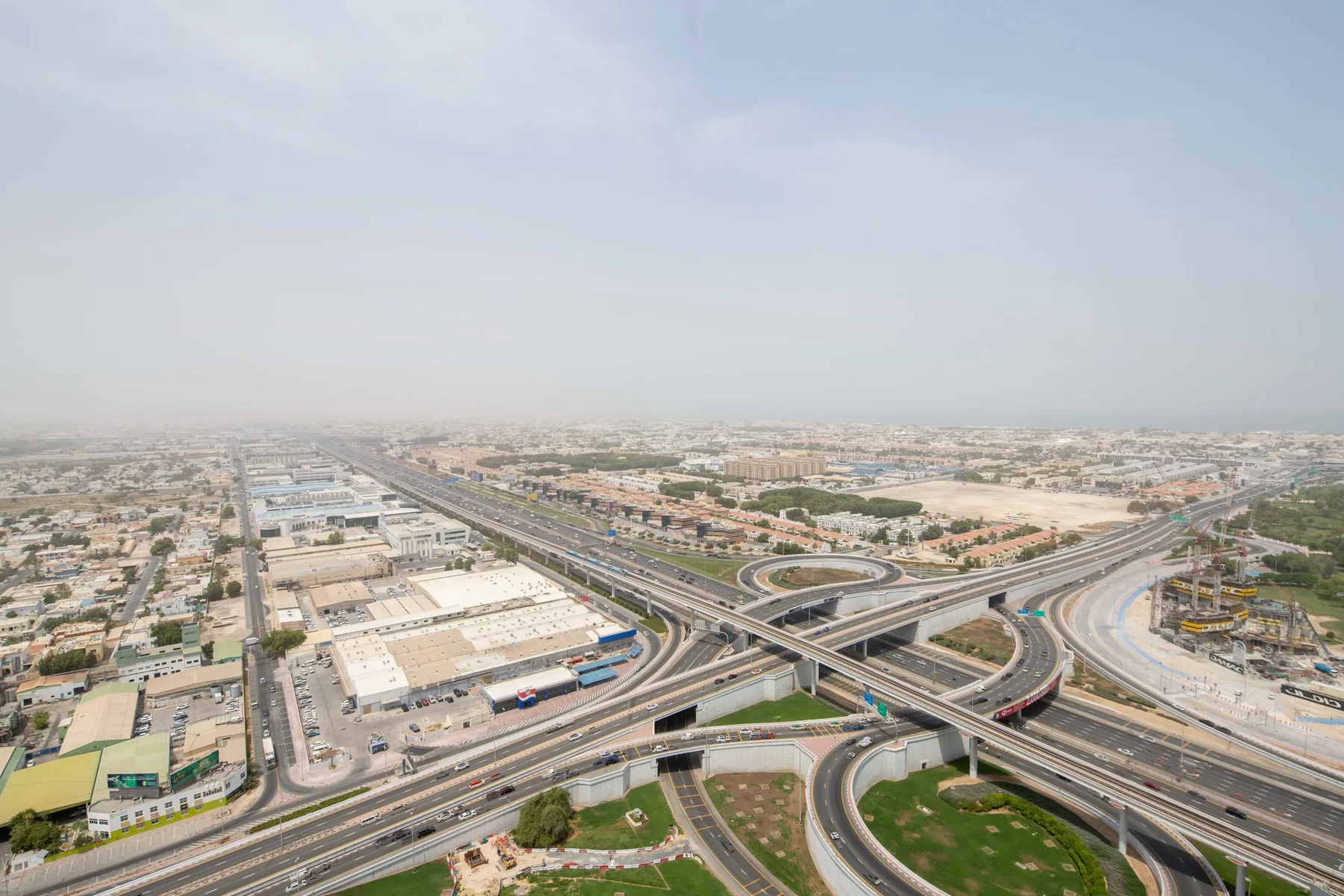 An aerial view shows a sprawling highway interchange amid a low-rise city.