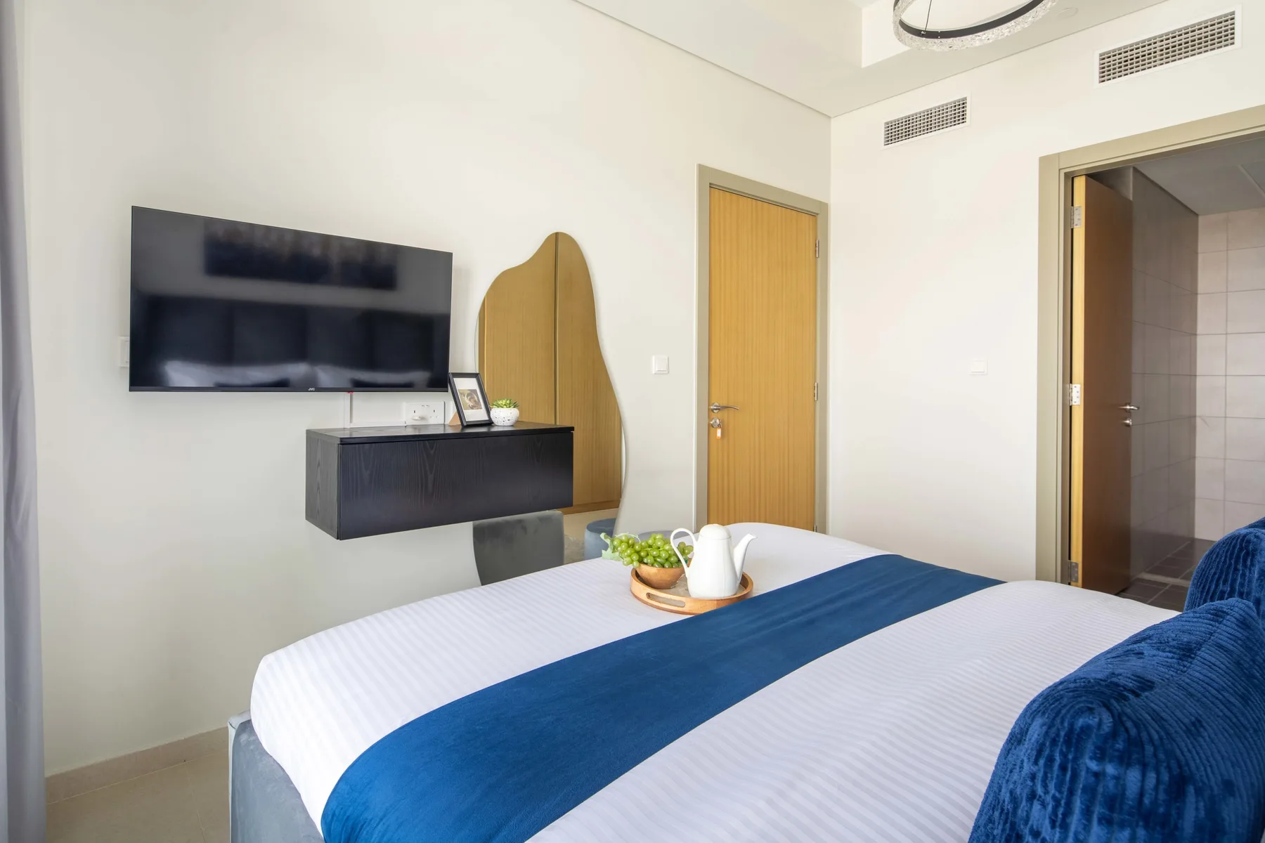 A bedroom with a neatly made bed and a wall-mounted television.