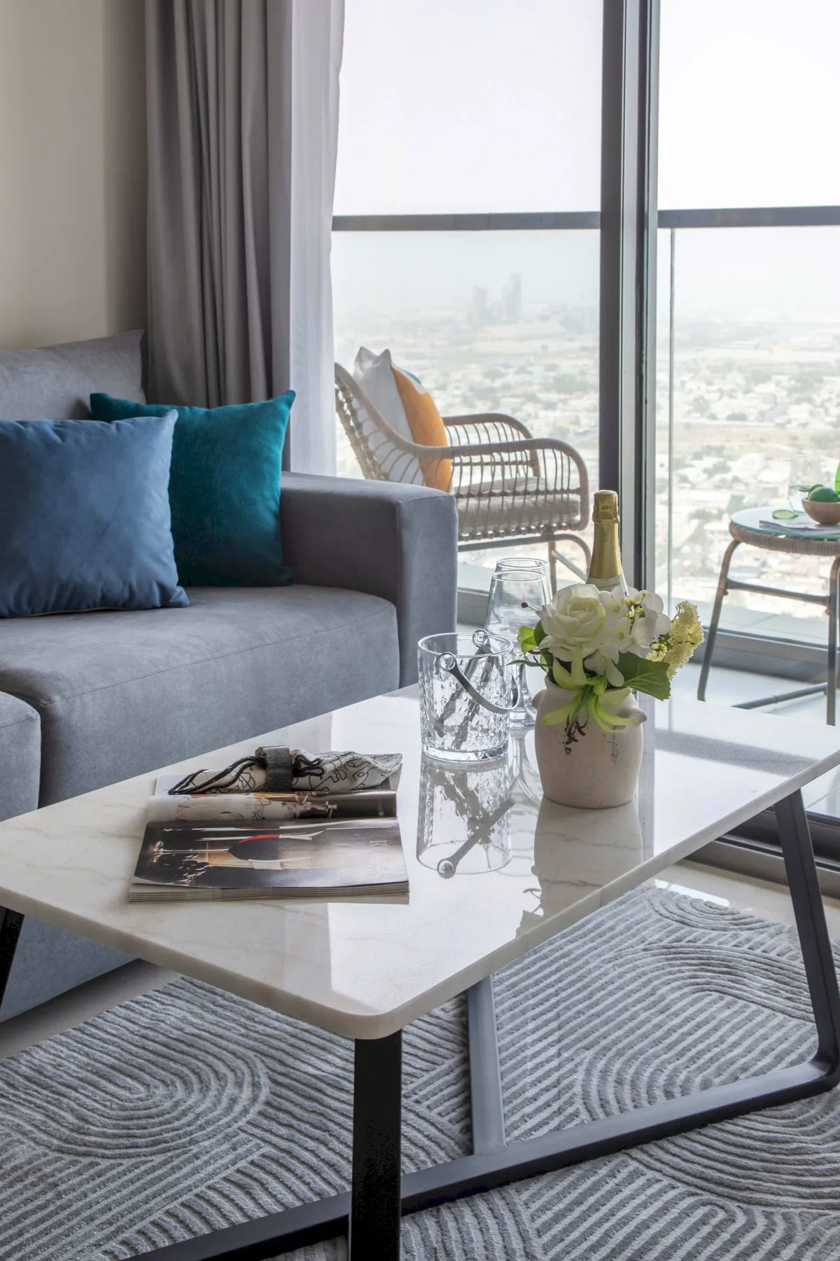 A living room with a gray sofa and a large window overlooking the city.