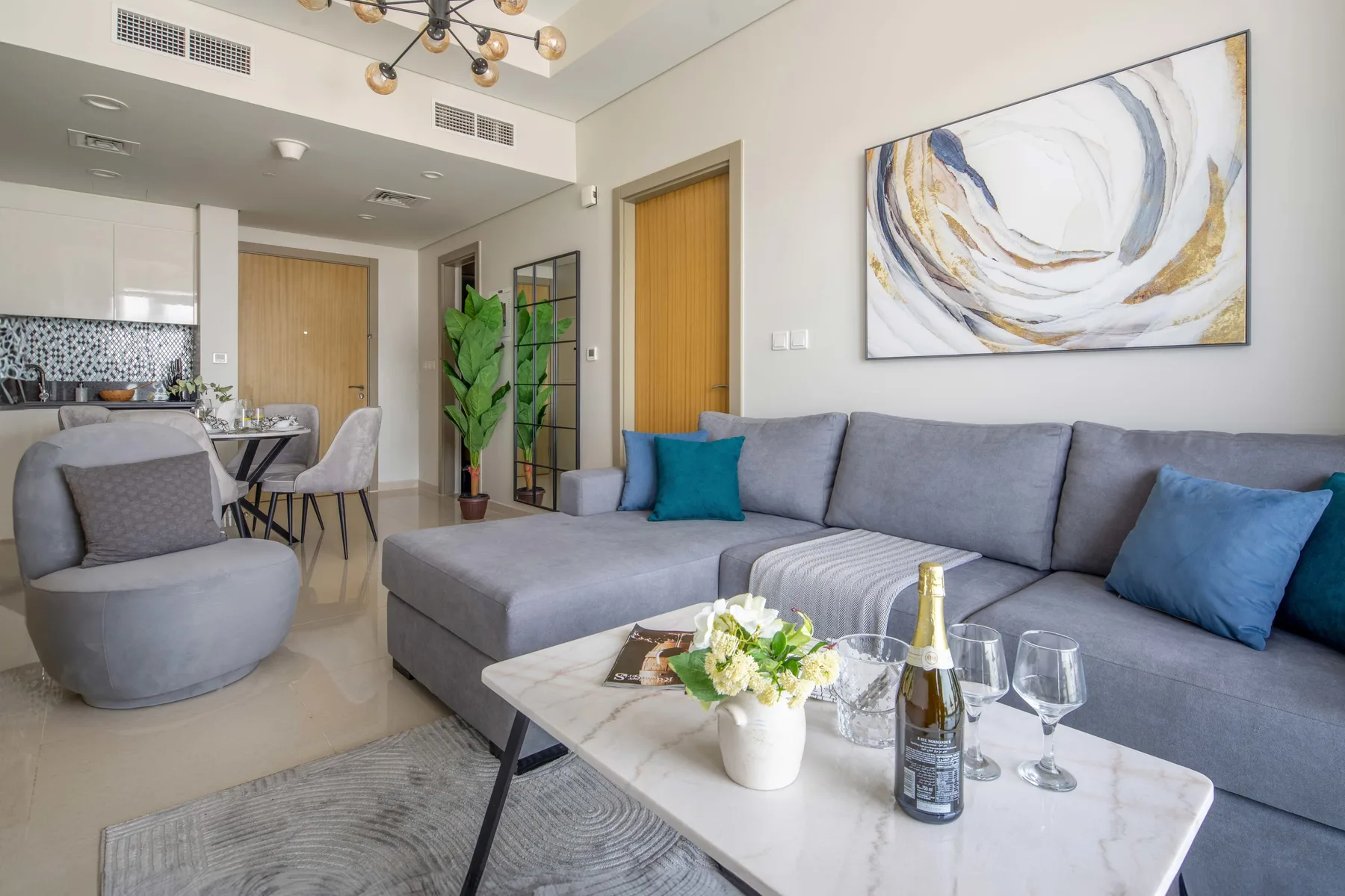 A living room with a gray sectional, coffee table, and abstract wall art.