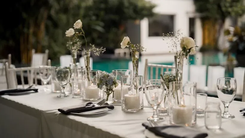 Mesa larga preparada para una recepción junto a la piscina.