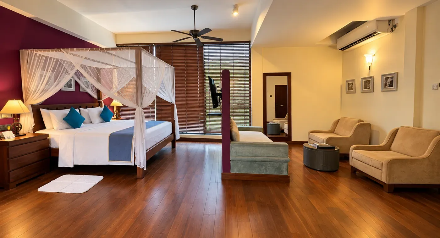 Suite Junior de lujo con cama con dosel, diván, sillones y ventanas altas.