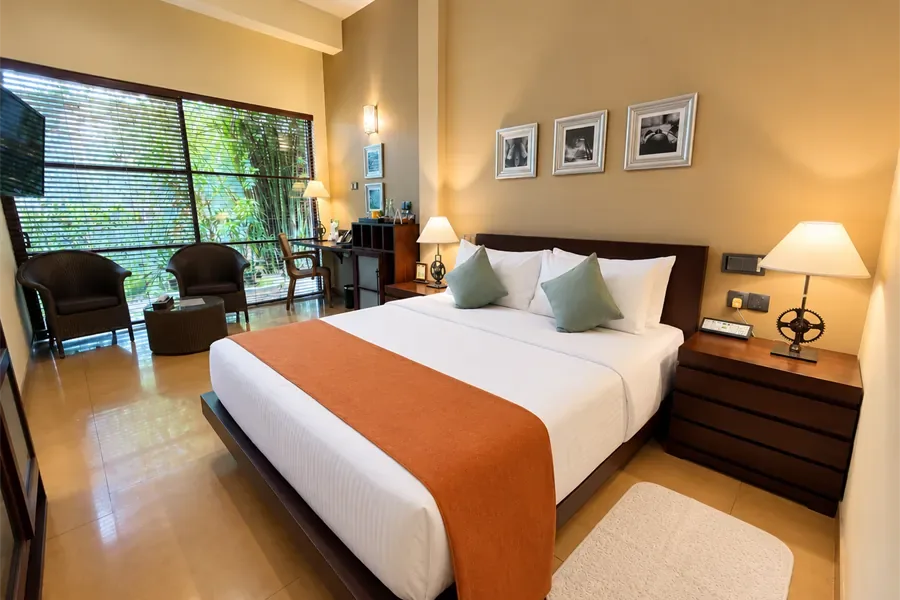 Habitación Deluxe con cama queen, sillones y vistas al jardín.