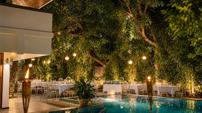 Mesas y faroles en el jardín junto a la piscina por la noche.