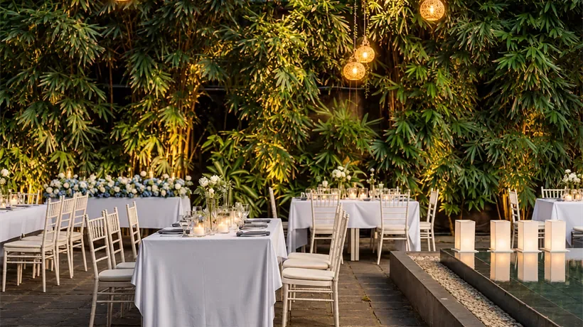 Recepción en el jardín con mesas redondas bajo las luces.