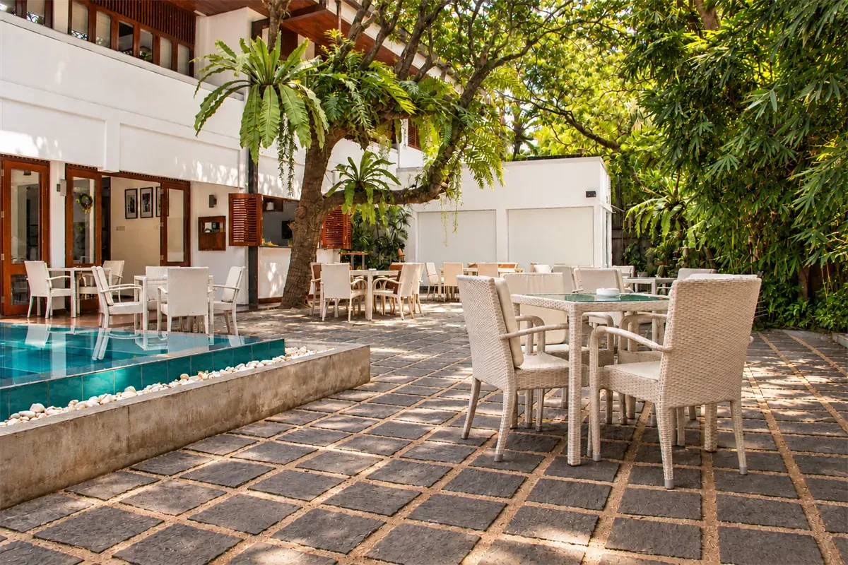 Mesas de comedor de Amber Poolside bajo un árbol junto a la piscina.