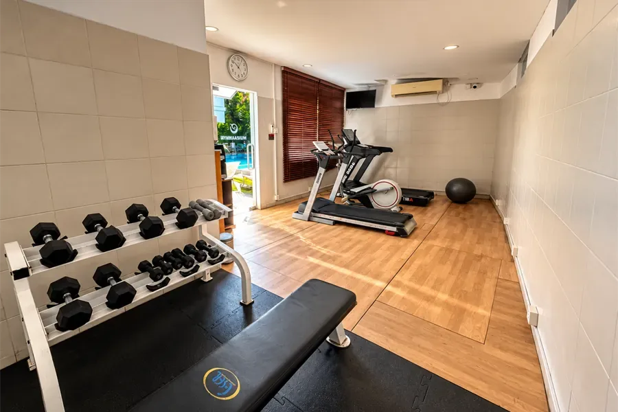Gimnasio con pesas, banco y cinta de correr.