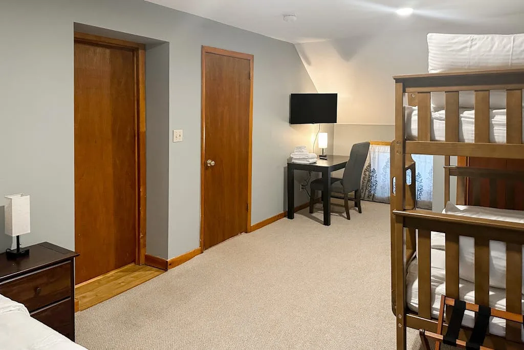 A bedroom with bunk beds, a desk, and a television.