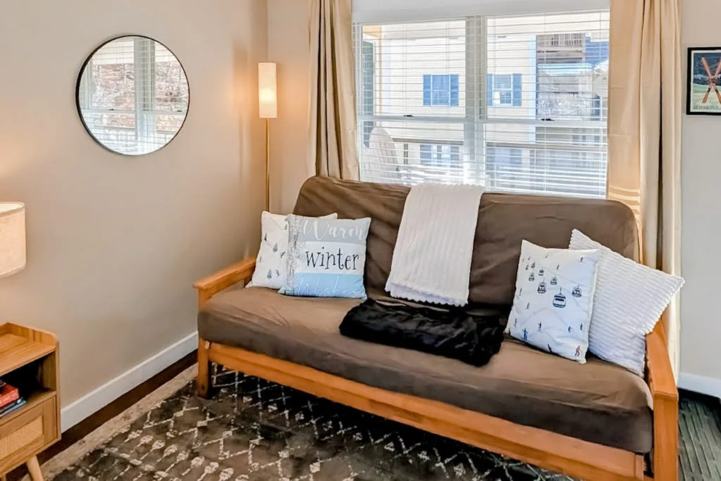 A living room with a brown sofa beneath a large window.