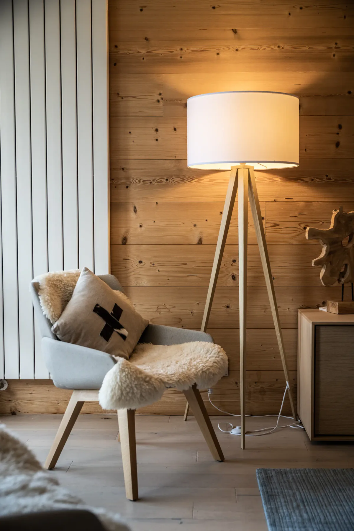Una zona de descanso del dormitorio muestra un sillón junto a una lámpara de pie encendida.