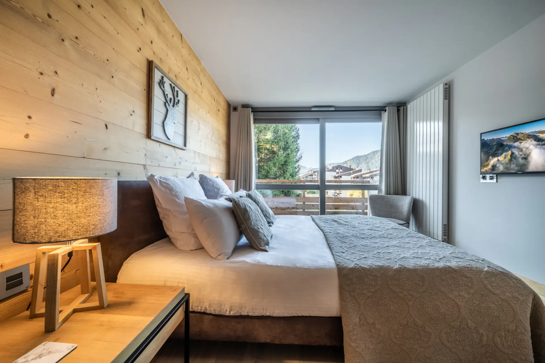 Un dormitorio con una cama grande y una ventana con vistas a árboles y montañas.
