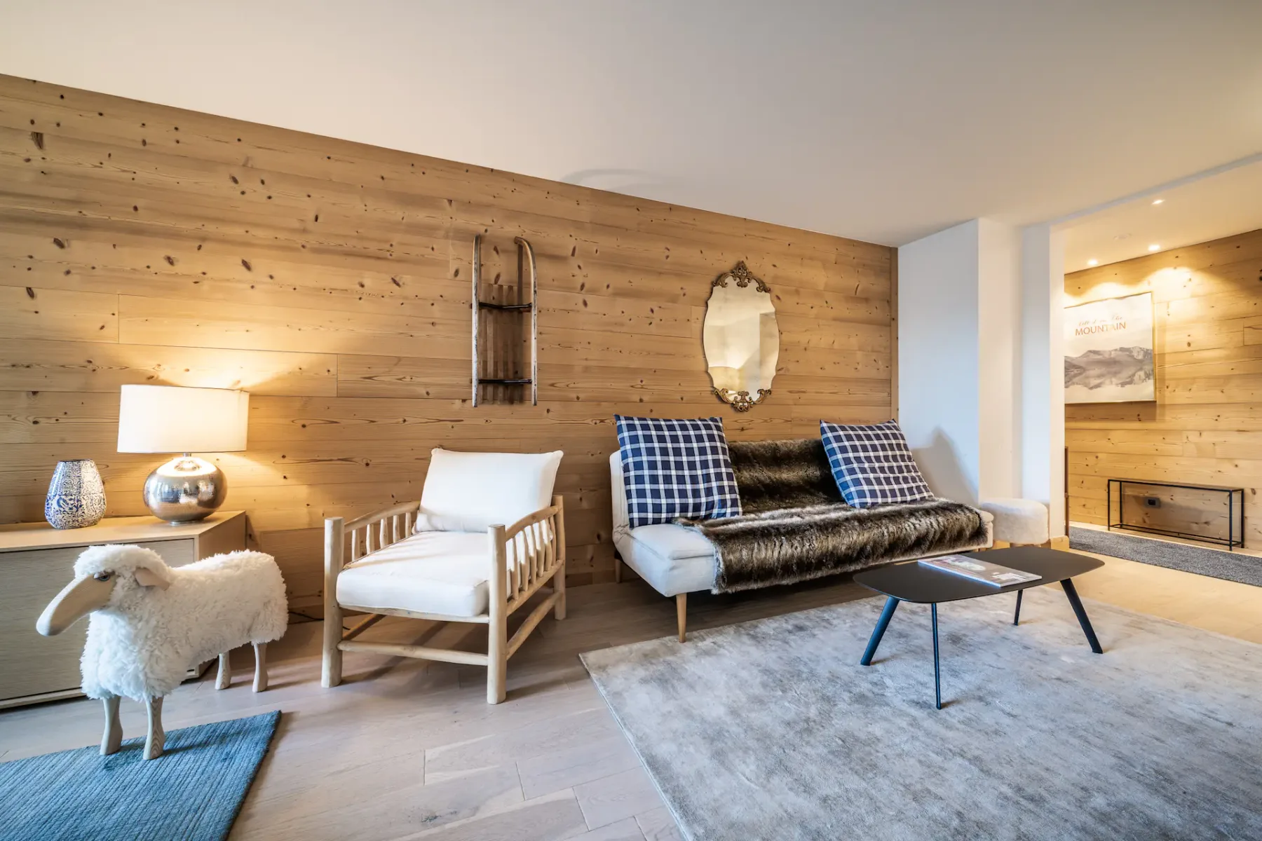Un salón con paredes revestidas de madera, asientos y una mesa de centro.