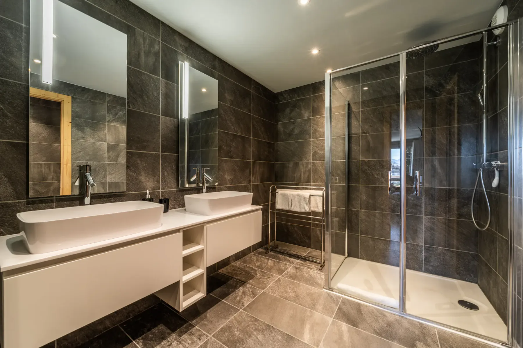 Un baño moderno con una ducha de vidrio y dos lavabos.