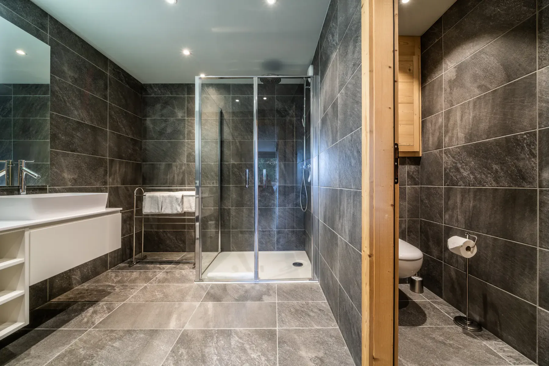 Baño alicatado con ducha de vidrio y lavabo.