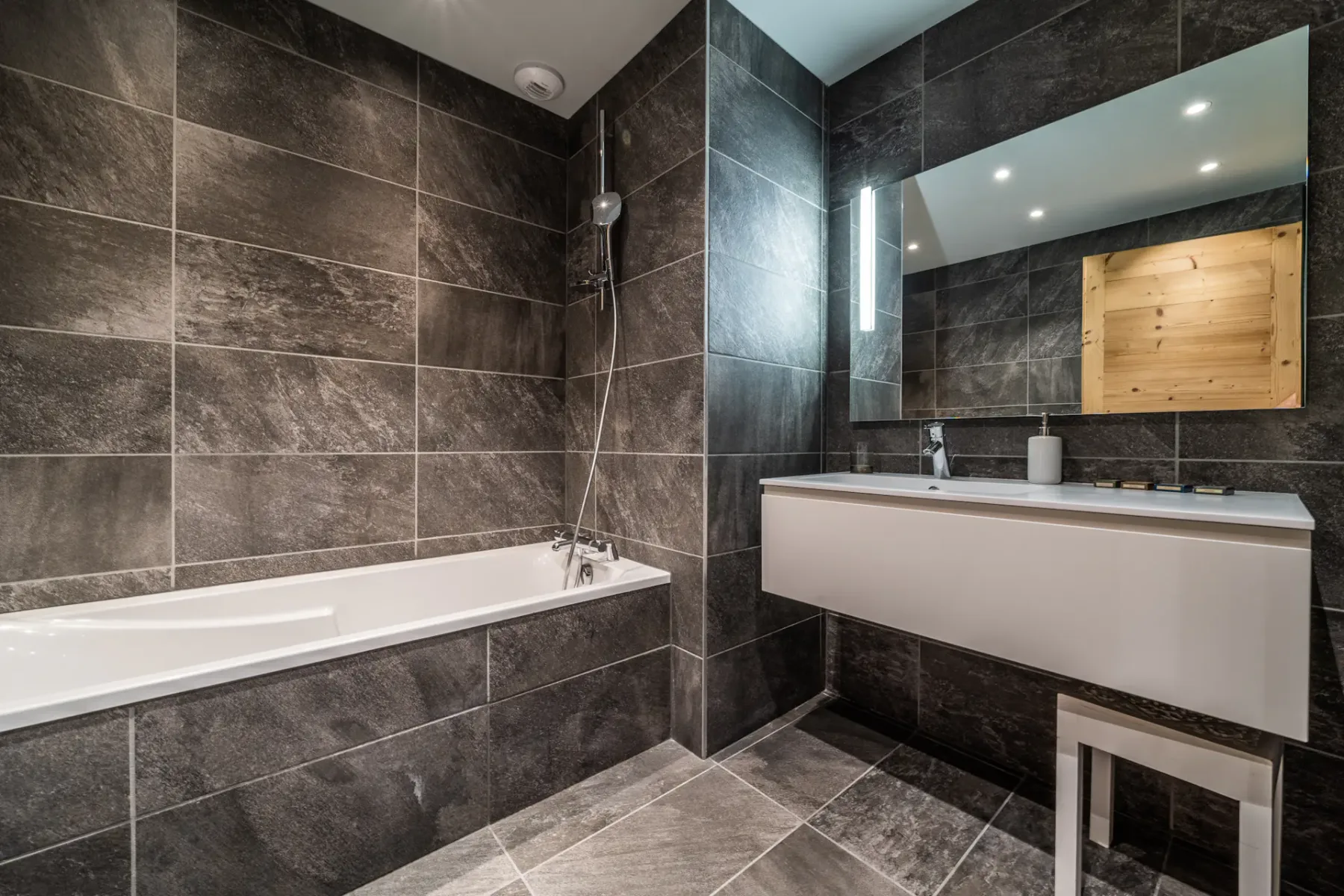 Un baño moderno con bañera y un amplio tocador bajo un espejo.