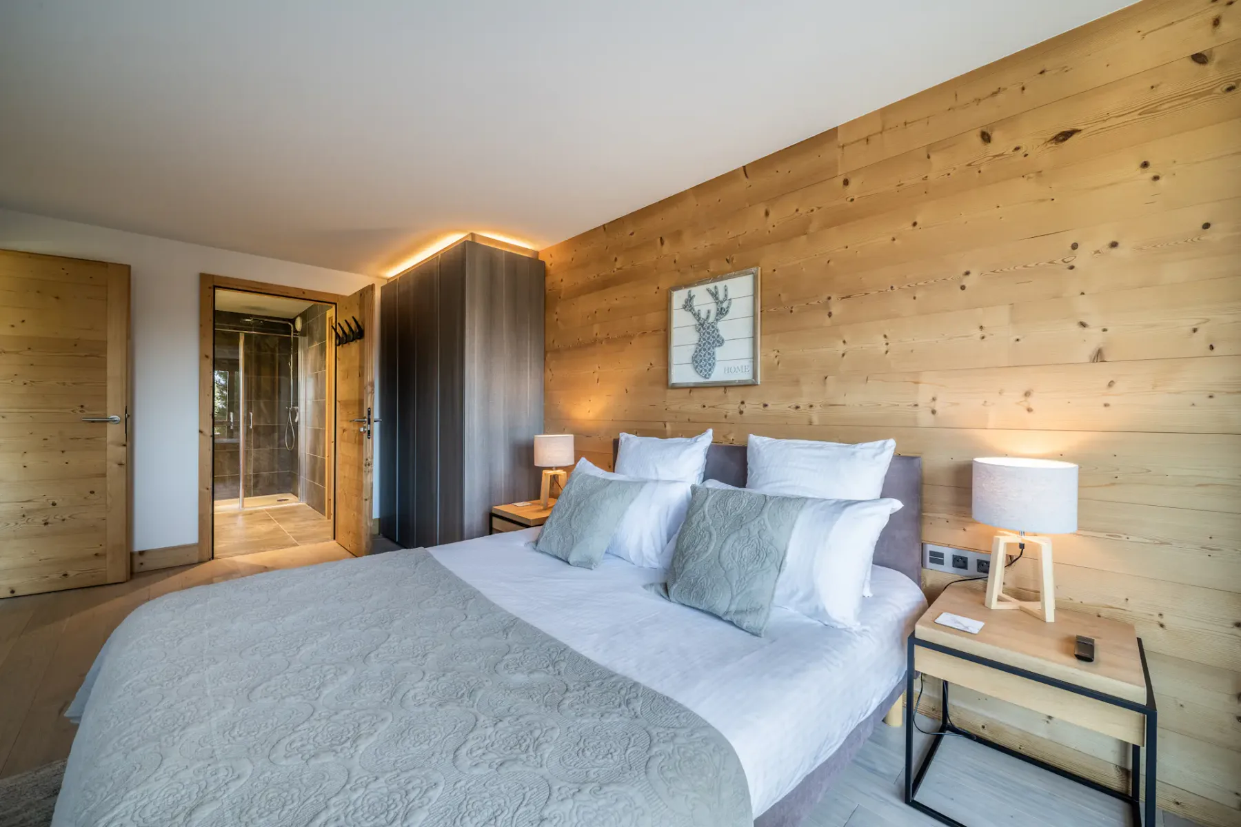Un dormitorio con una cama bien hecha y paredes revestidas de madera cálida.