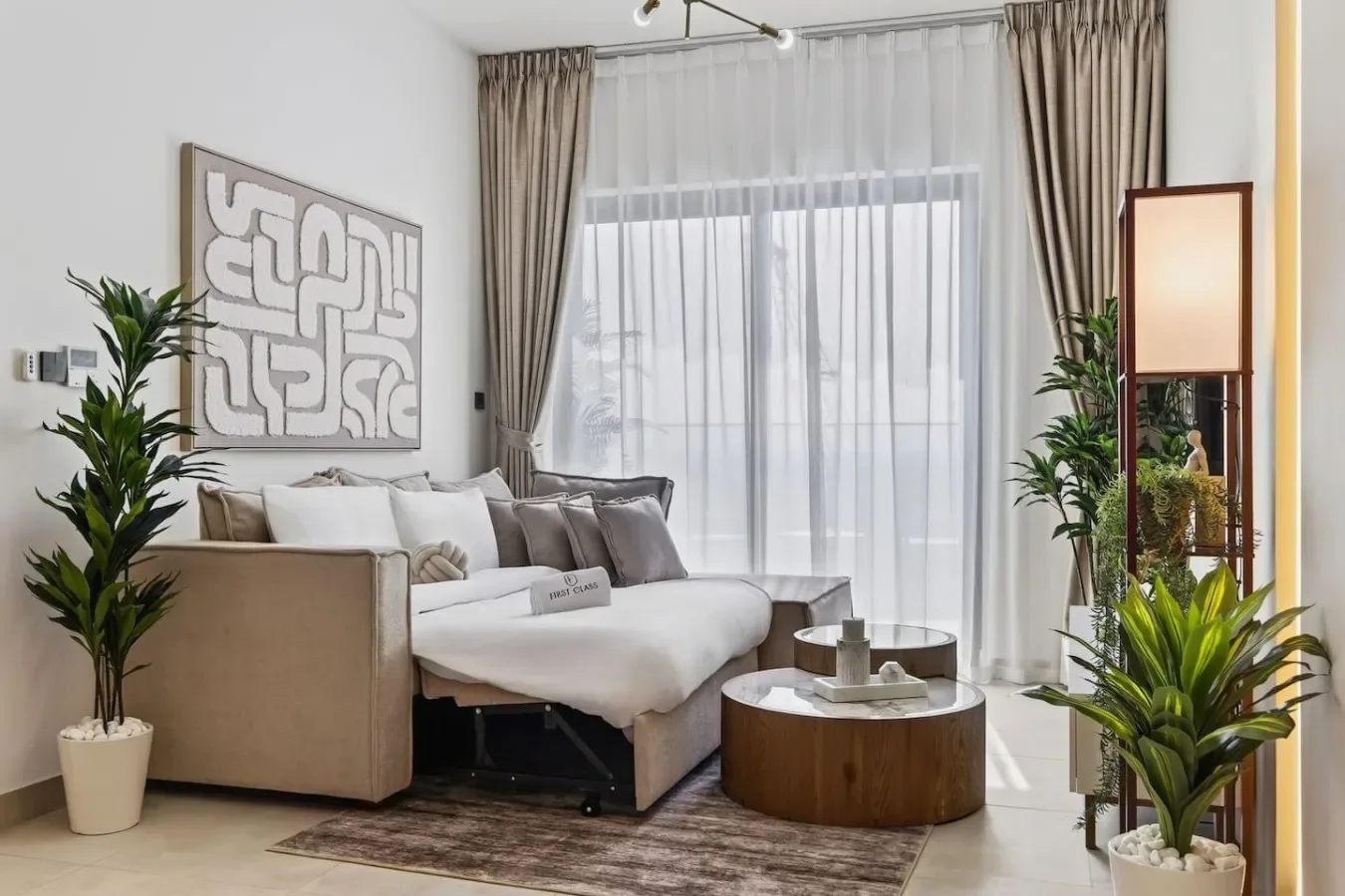 Una sala luminosa con una zona de asientos junto a grandes ventanas con cortinas.