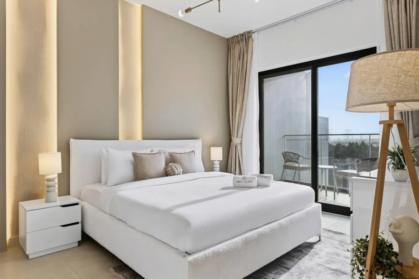 Un dormitorio luminoso con una cama blanca junto a puertas corredizas de vidrio.