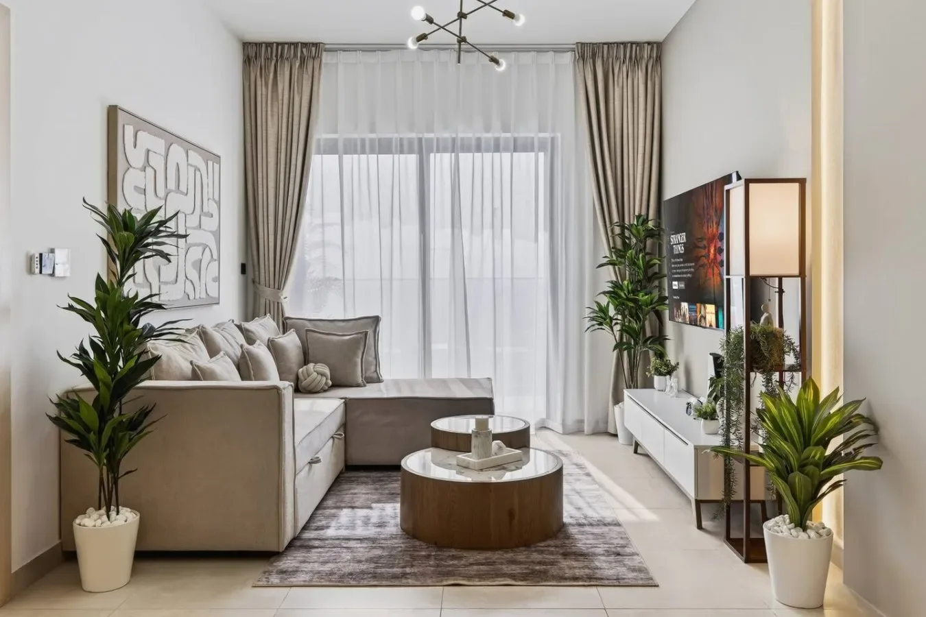 Una sala de estar con sofá seccional, mesas de centro y plantas.