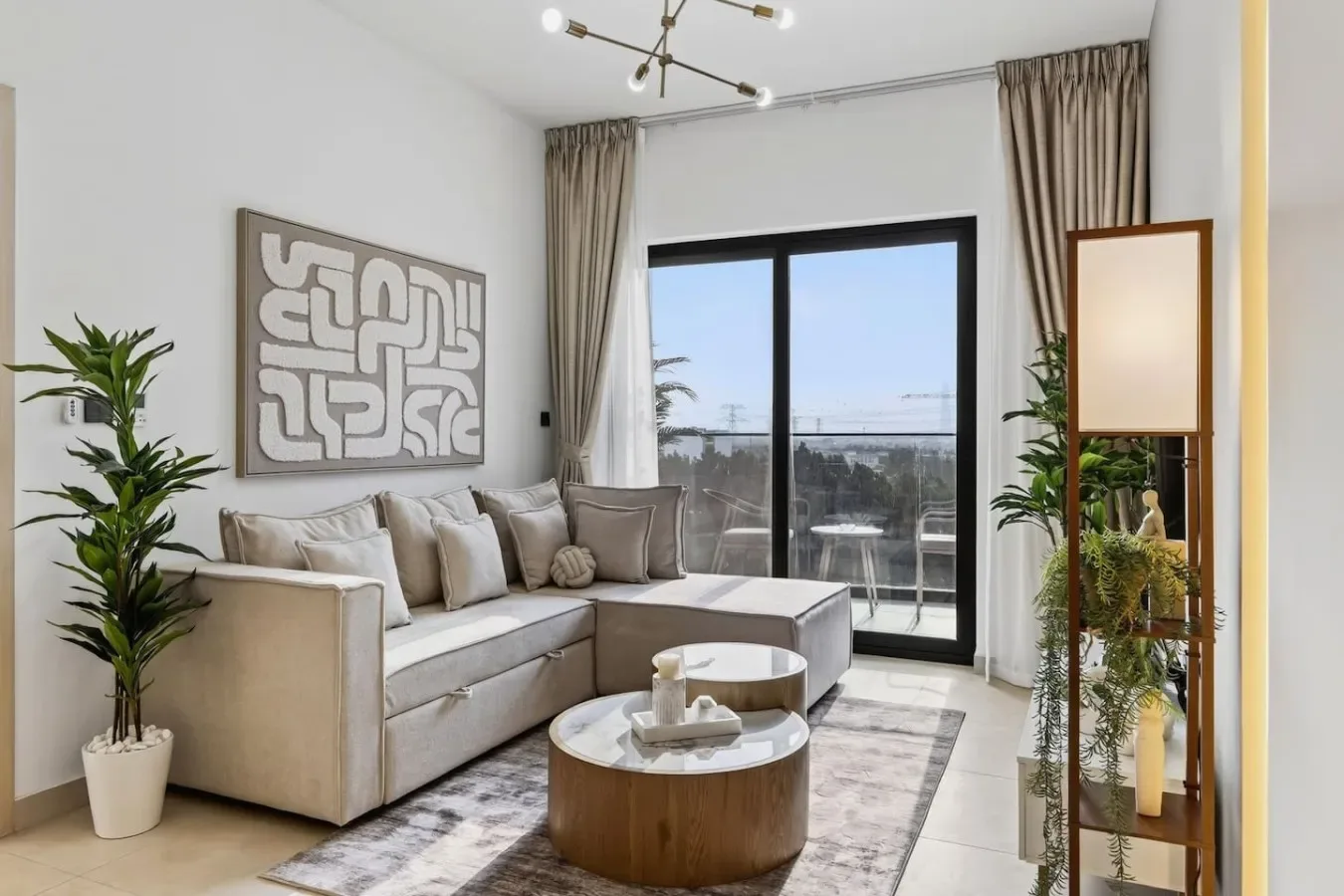 Una sala luminosa con un sofá beige y puertas de vidrio que dan a un balcón.