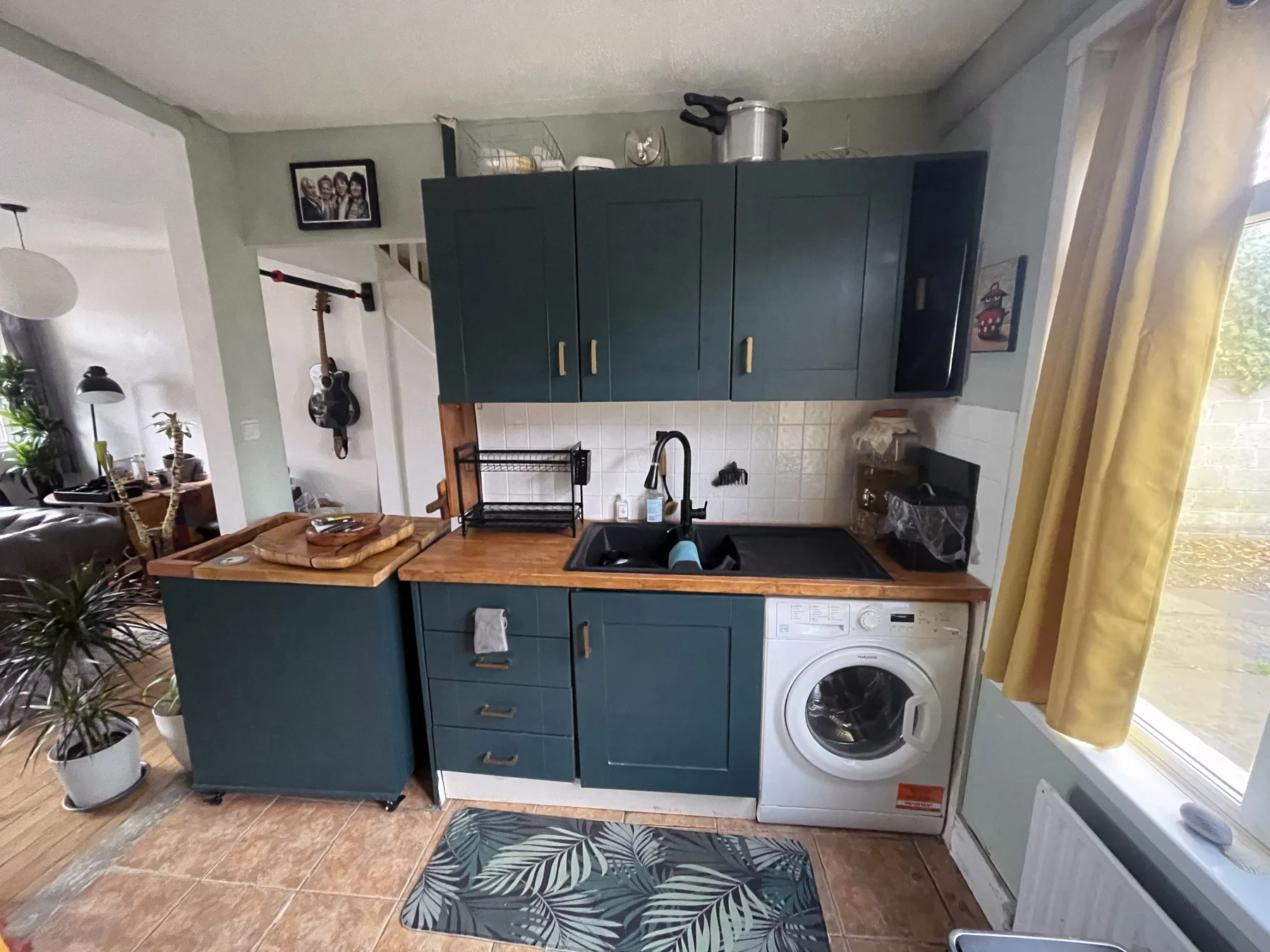 A compact kitchen with dark cabinets, a sink, and a washing machine.