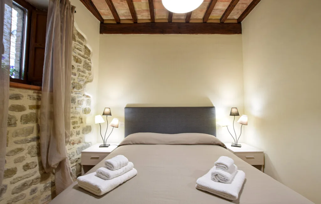 A bedroom with a neatly made bed and matching bedside lamps.