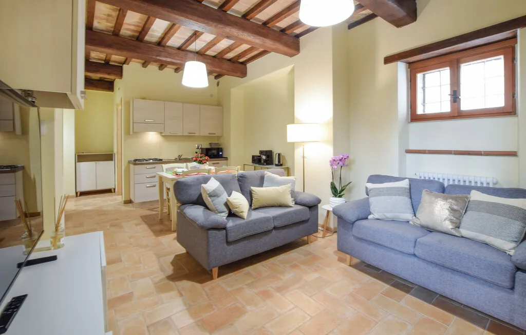 A living room with two seating areas, a dining table, and exposed ceiling beams.