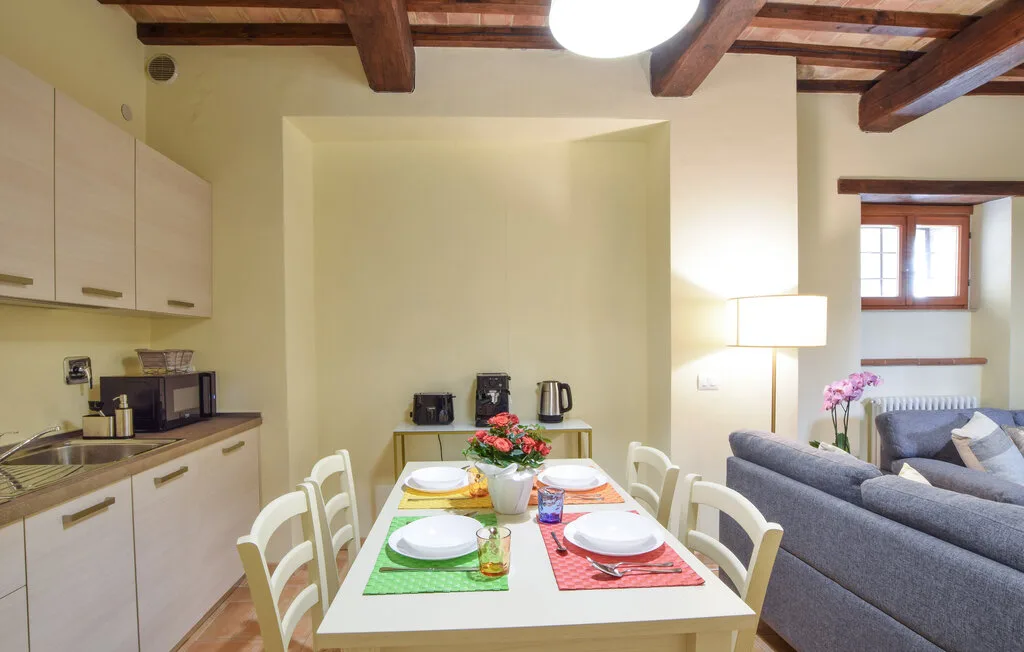 A dining table is set beside a compact kitchen and living area.