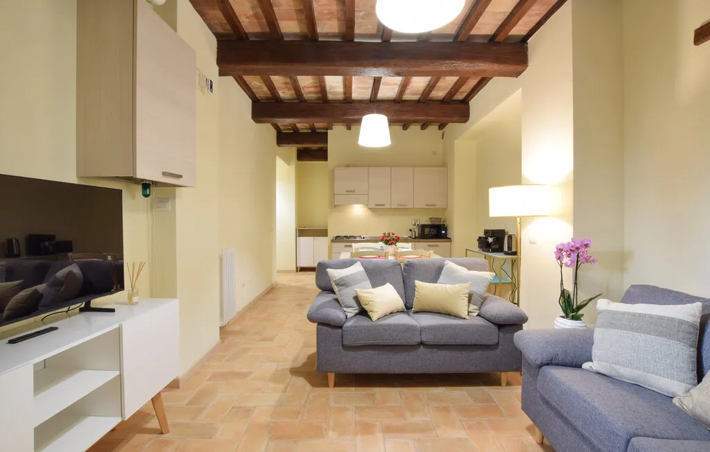 A living room with gray seating, a television, and an open kitchen.