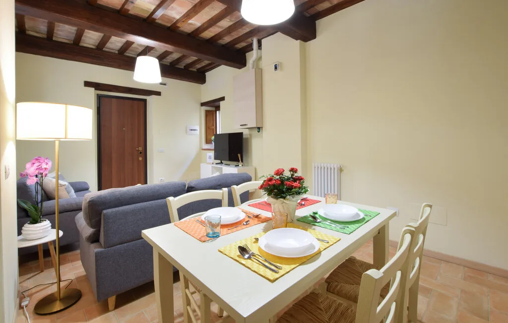 A dining area with a set table beside a living room seating area.