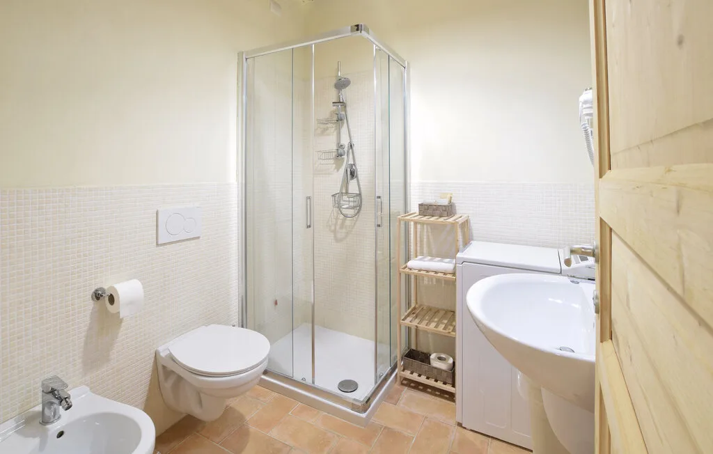 A bright bathroom with a glass shower, toilet, and sink.