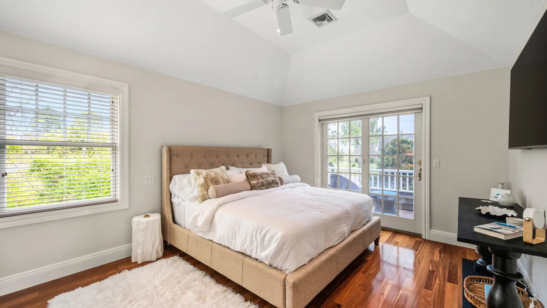 Un dormitorio luminoso con una cama bien tendida y ventanas con vistas a la vegetación.