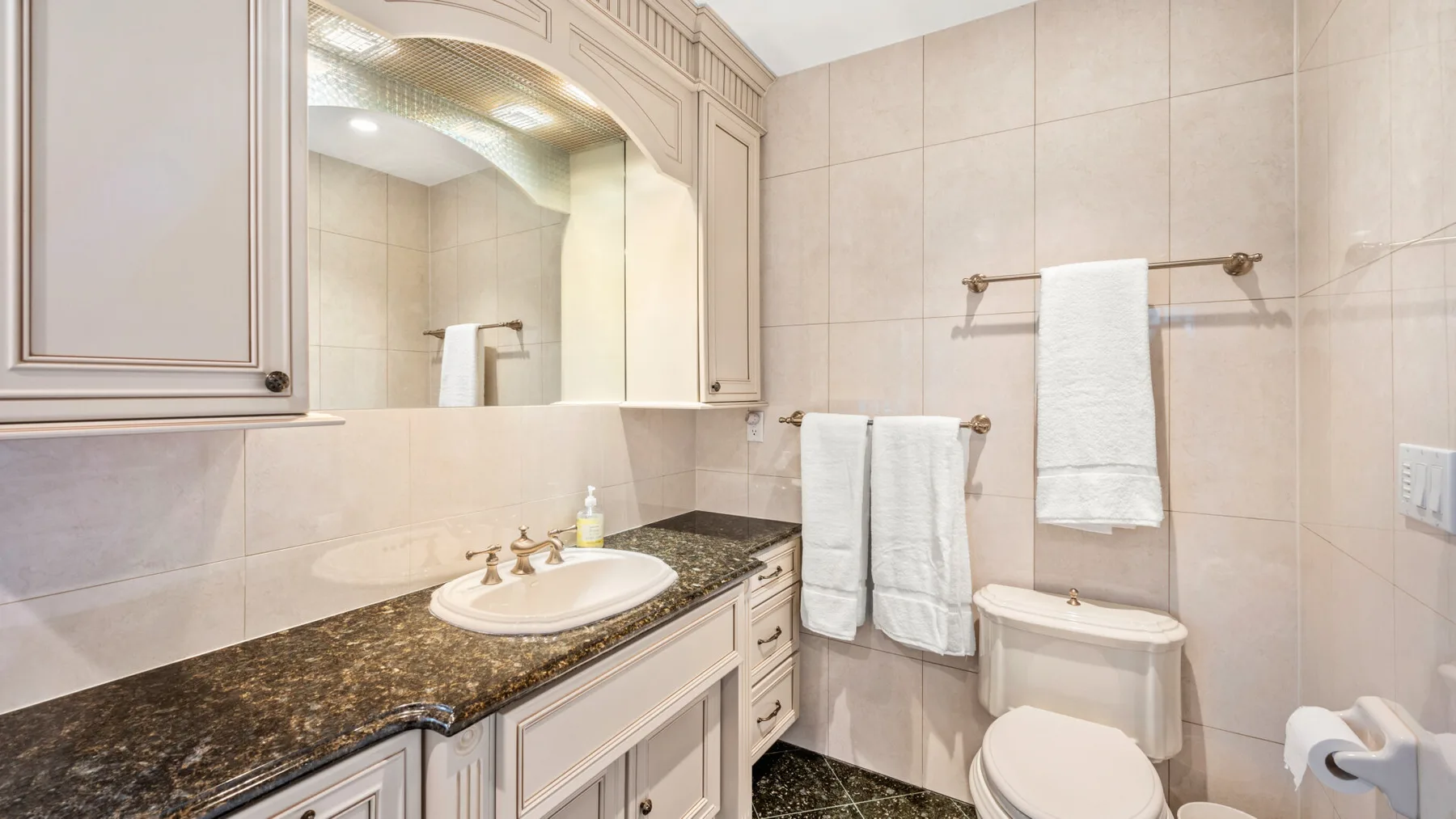 Un baño con azulejos, lavabo con espejo y toallas.