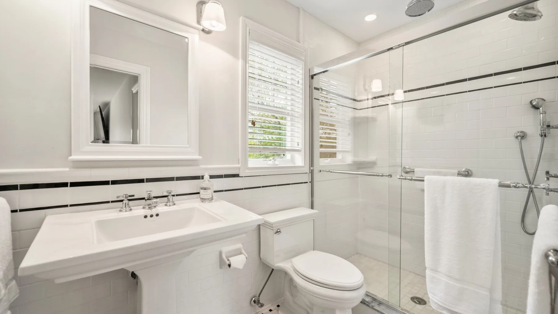 Un baño luminoso con lavabo y ducha con mampara de vidrio.