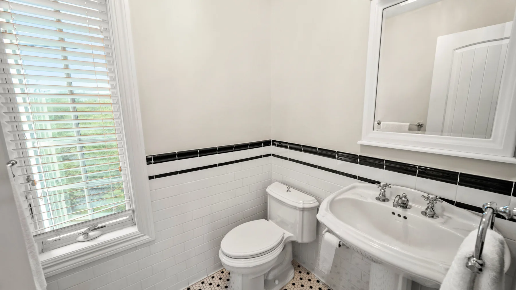 Un baño con inodoro, lavabo y una ventana con persianas.
