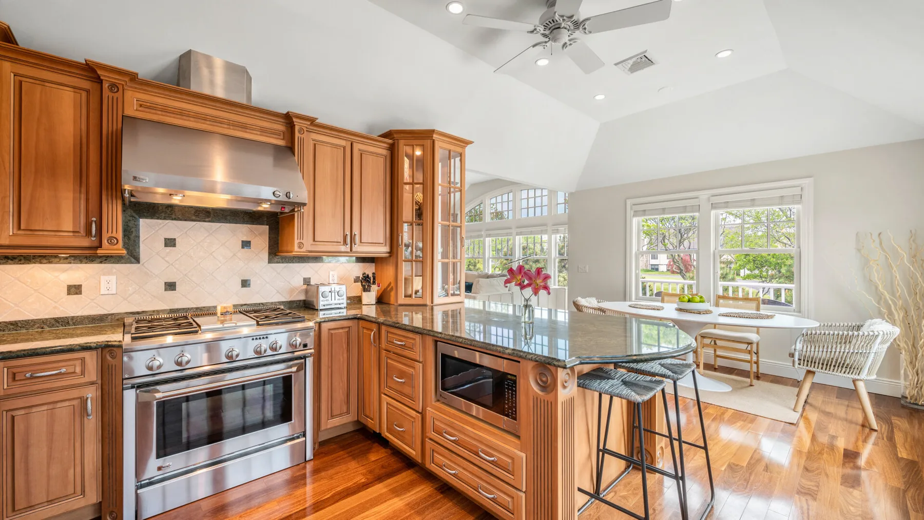 Una cocina luminosa con gabinetes de madera, electrodomésticos de acero inoxidable y una isla central.