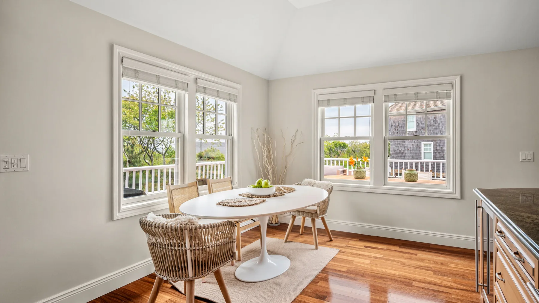 Un comedor luminoso con una mesa y ventanas grandes.