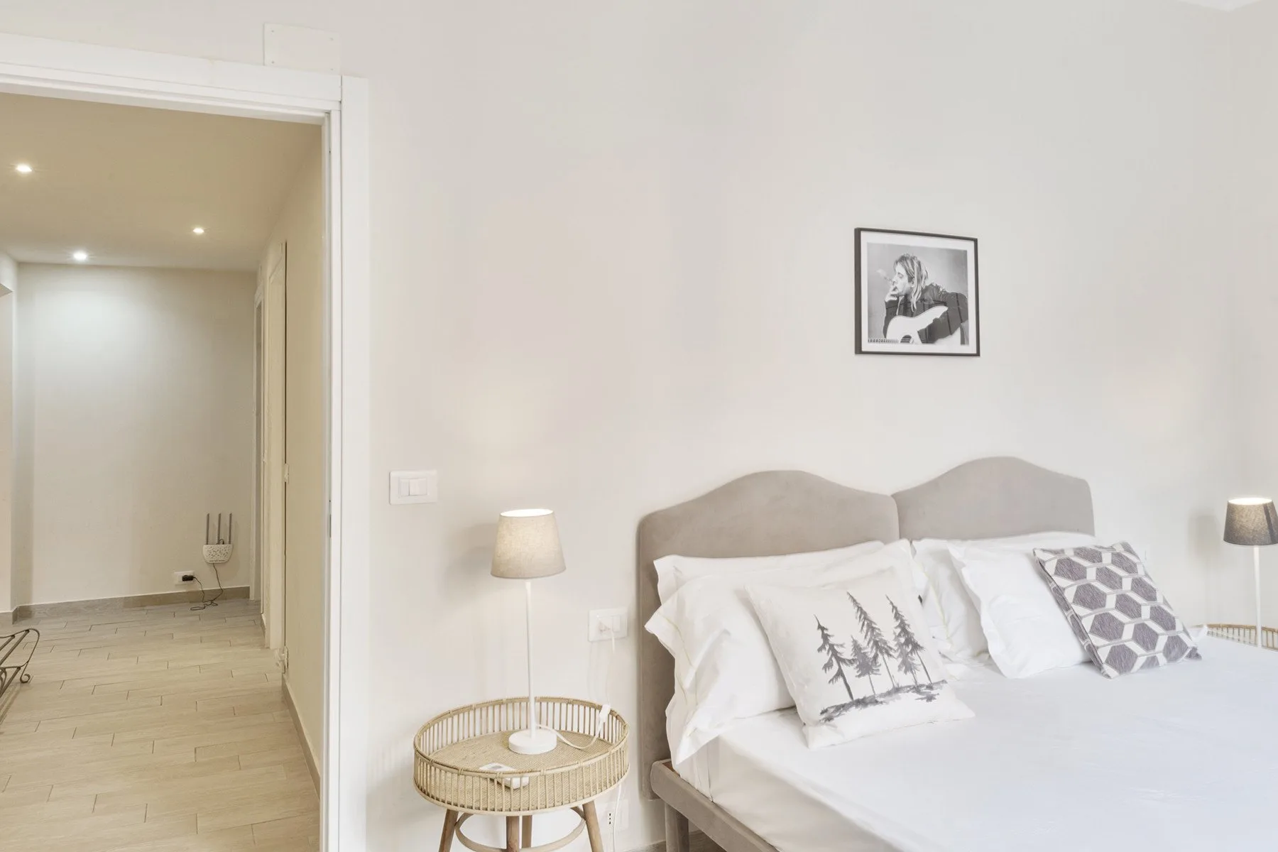 A bright bedroom with a bed, bedside tables, and framed wall art.
