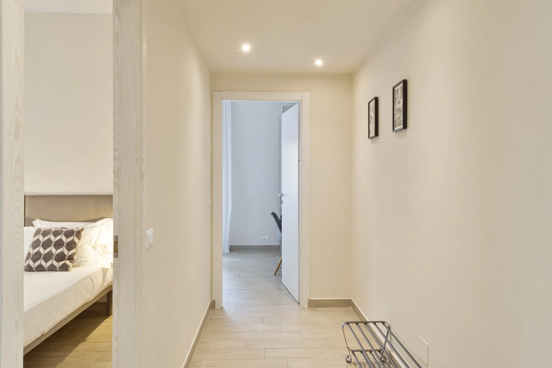 A bright hallway leads past an open doorway, with a bedroom visible to the side.