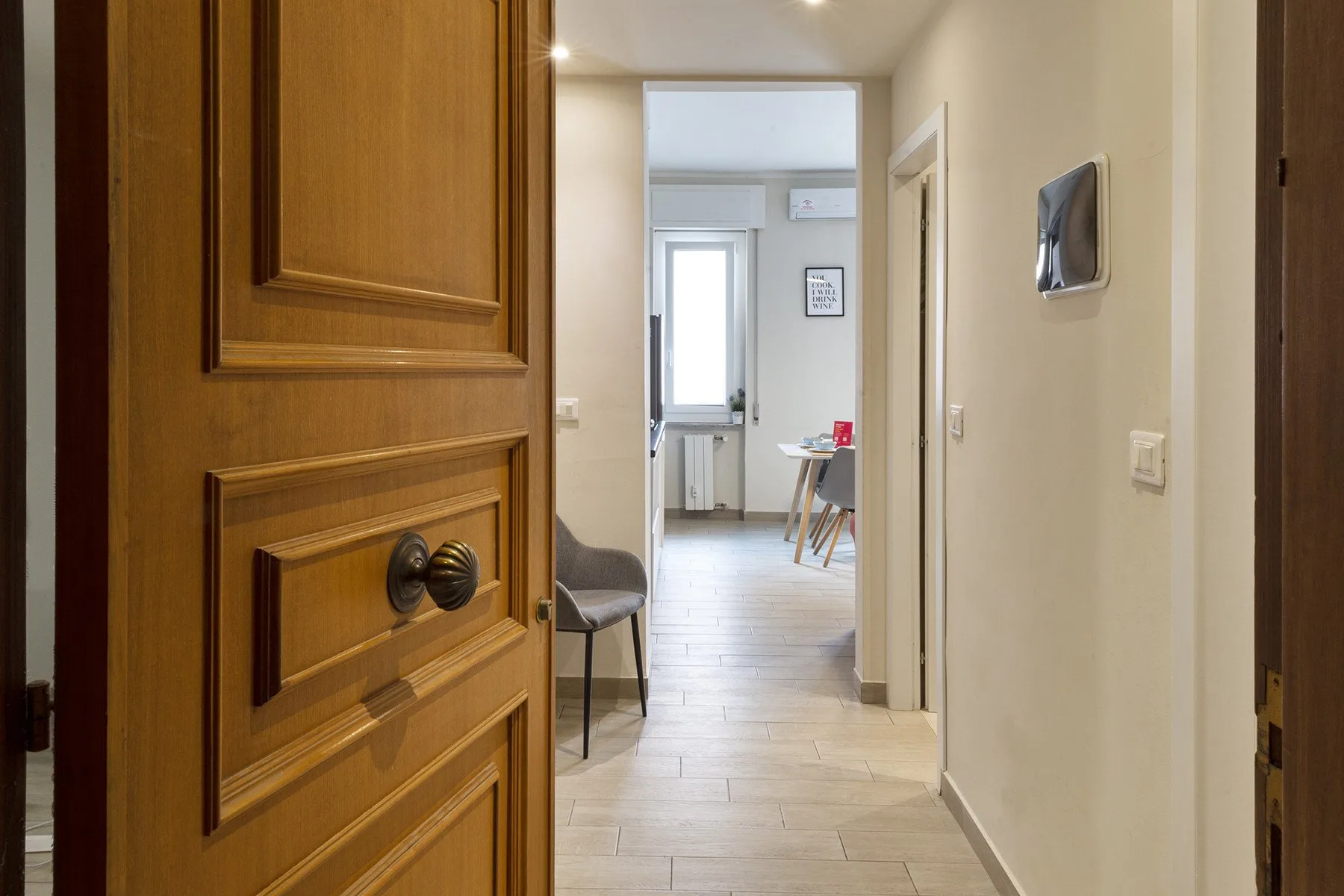 A tiled hallway leads to a bright room with a small table.
