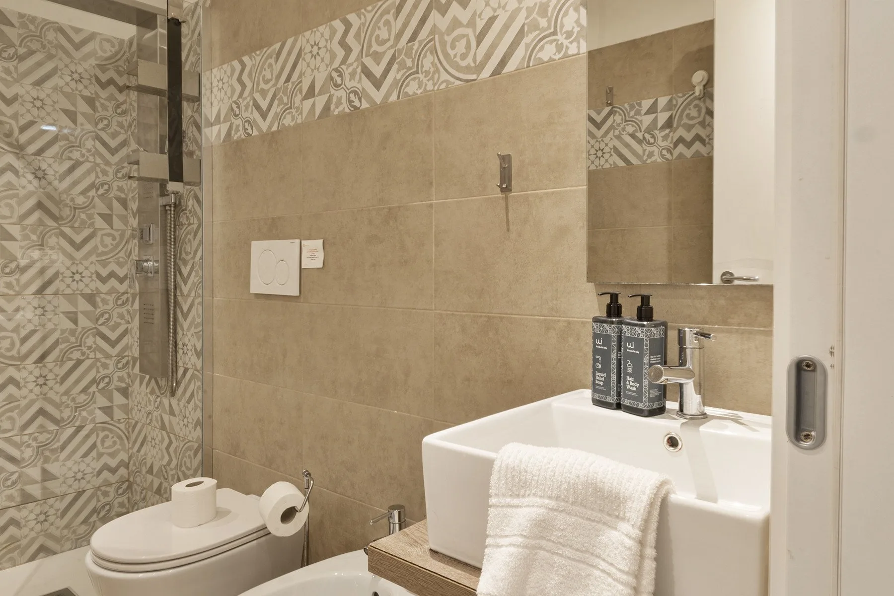A bathroom with a sink, toilet, and patterned tile accents.