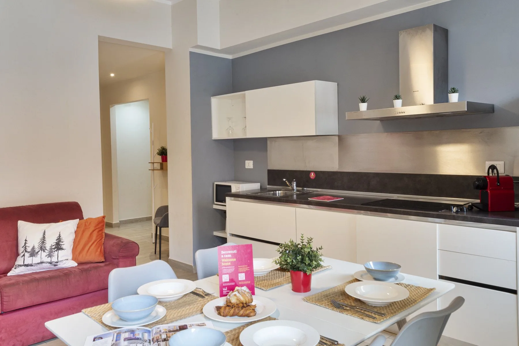 A dining table sits in front of a modern kitchen with gray cabinets and counters.