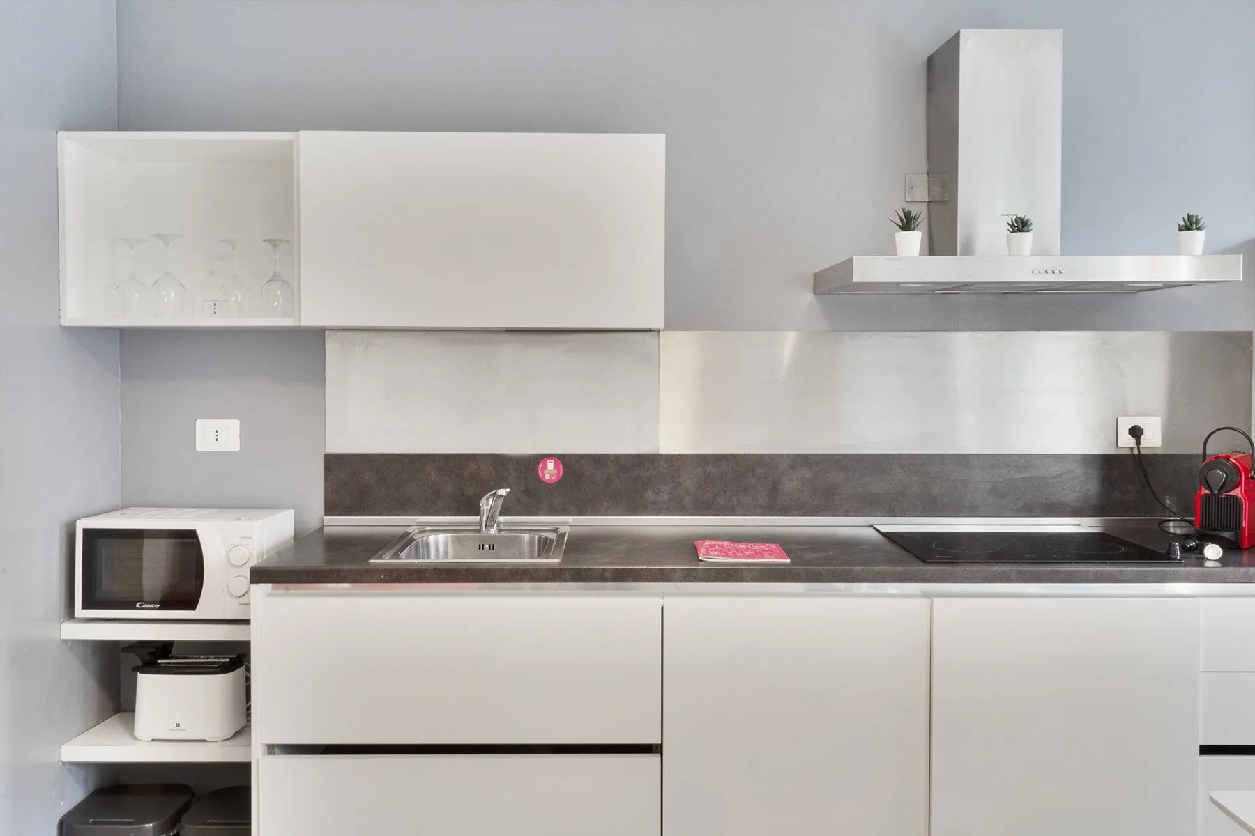 A modern kitchen with white cabinetry, a countertop, and a sink.
