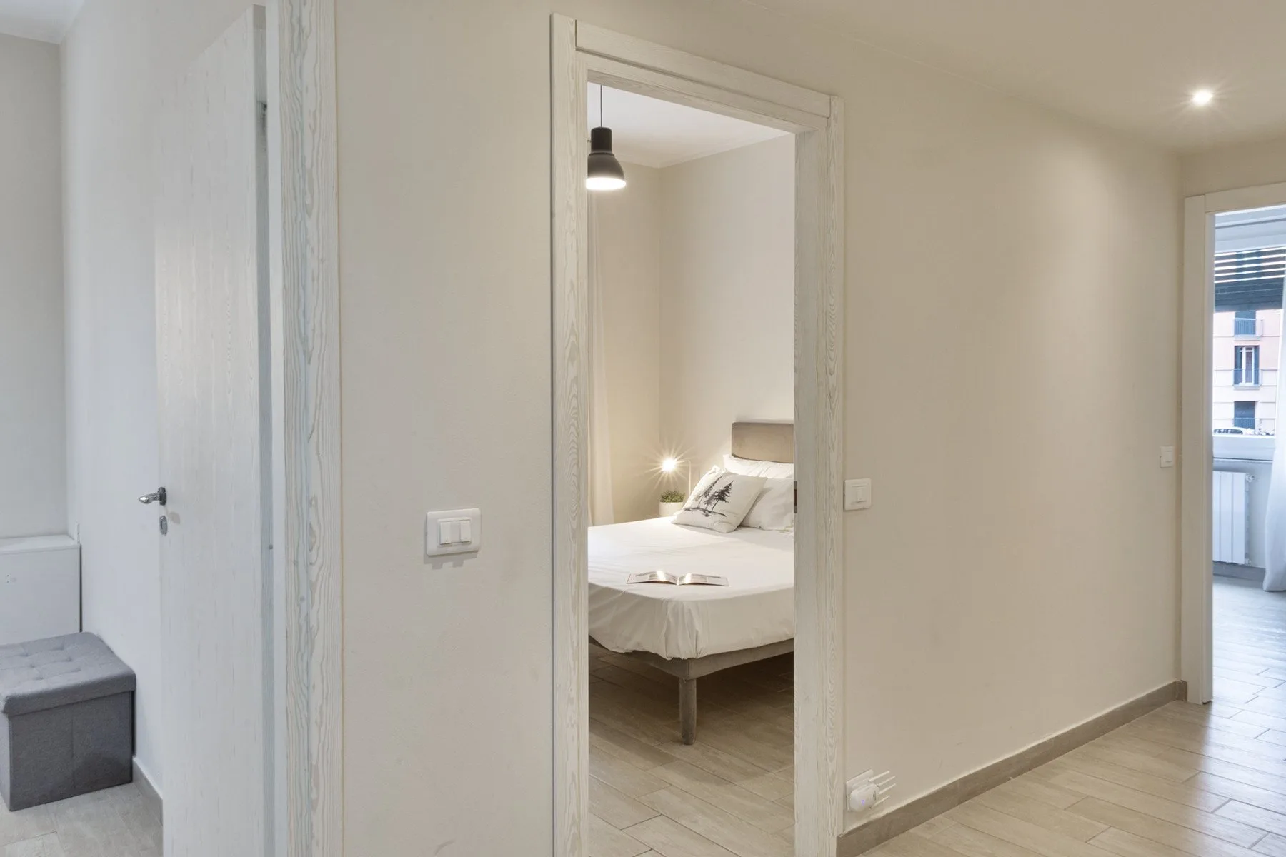 A hallway opens onto a bedroom, with a bed visible through the doorway.