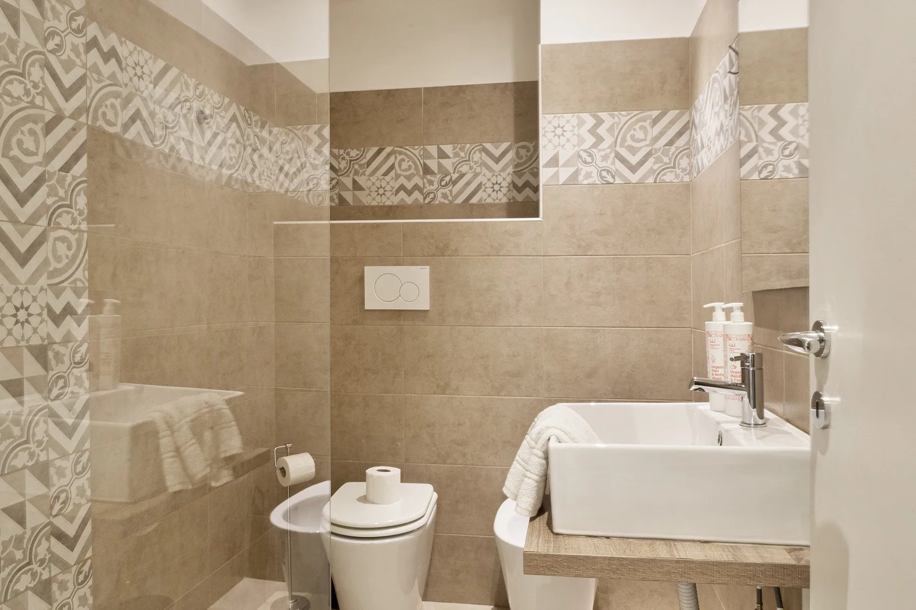 A tiled bathroom with a bathtub, toilet, and sink.