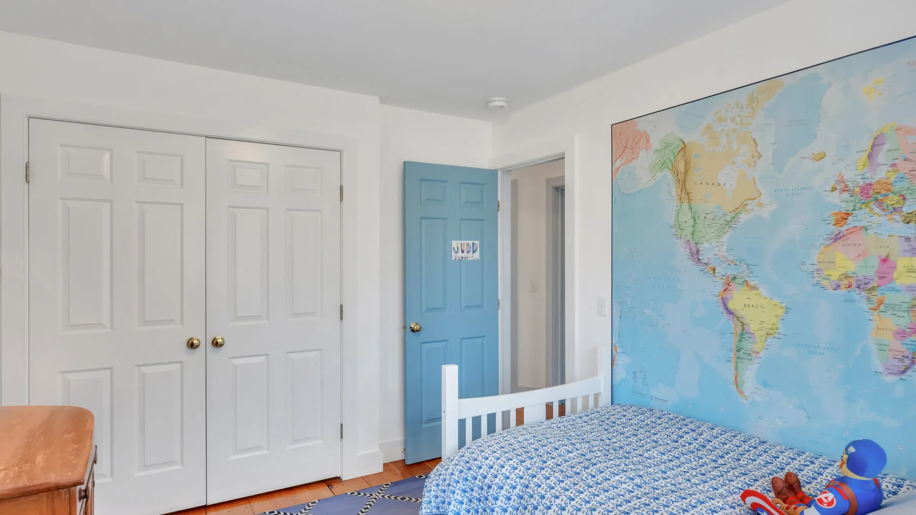 Un dormitorio con una cama junto a un gran mapa mural del mundo.