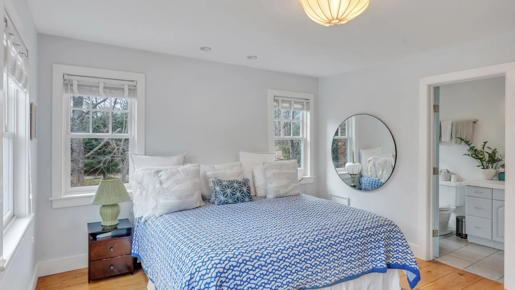 Un dormitorio luminoso con una colcha azul estampada y ventanas.