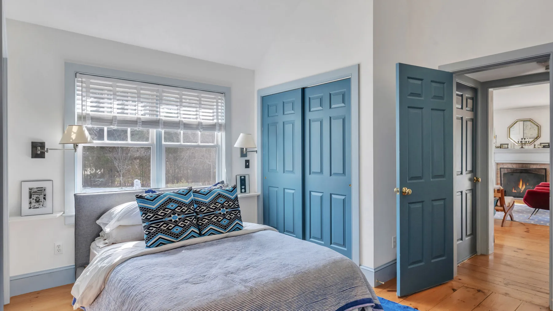 Un dormitorio con una cama junto a puertas azules con paneles y una ventana.